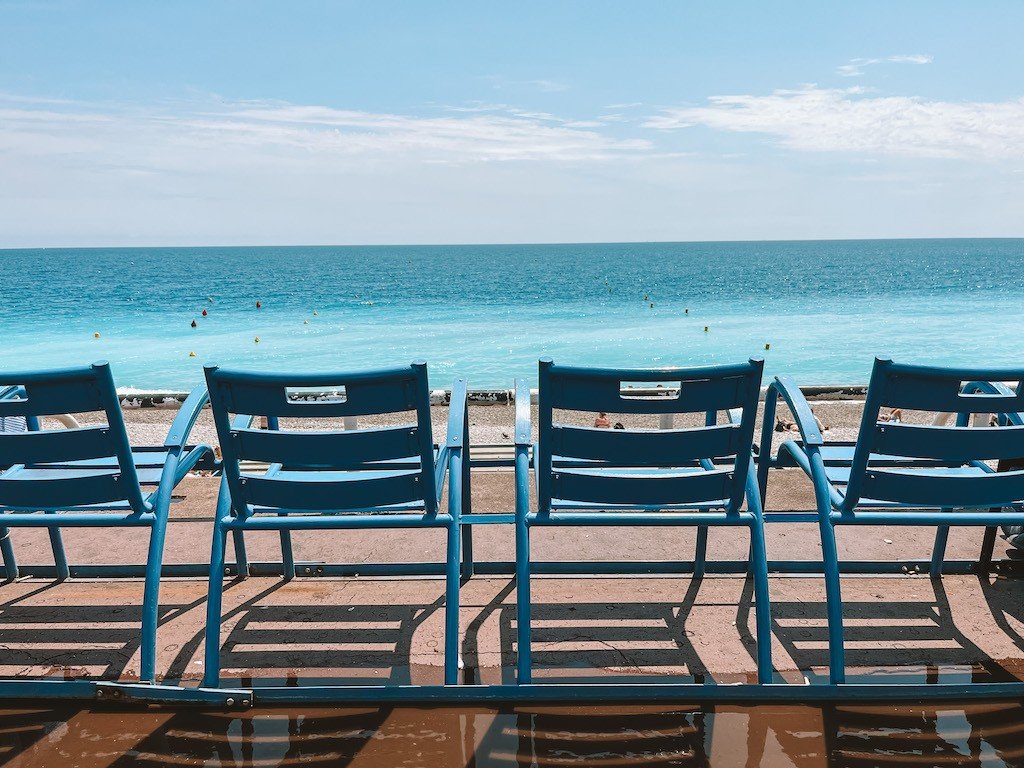 Blaue Stühle mit Blick auf das Meer am Nizza Strand