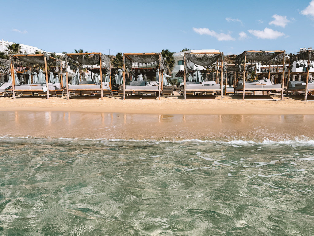 Strandbetten und türkisblaues, klares Wasser am Strand Platis Gialos auf Mykonos