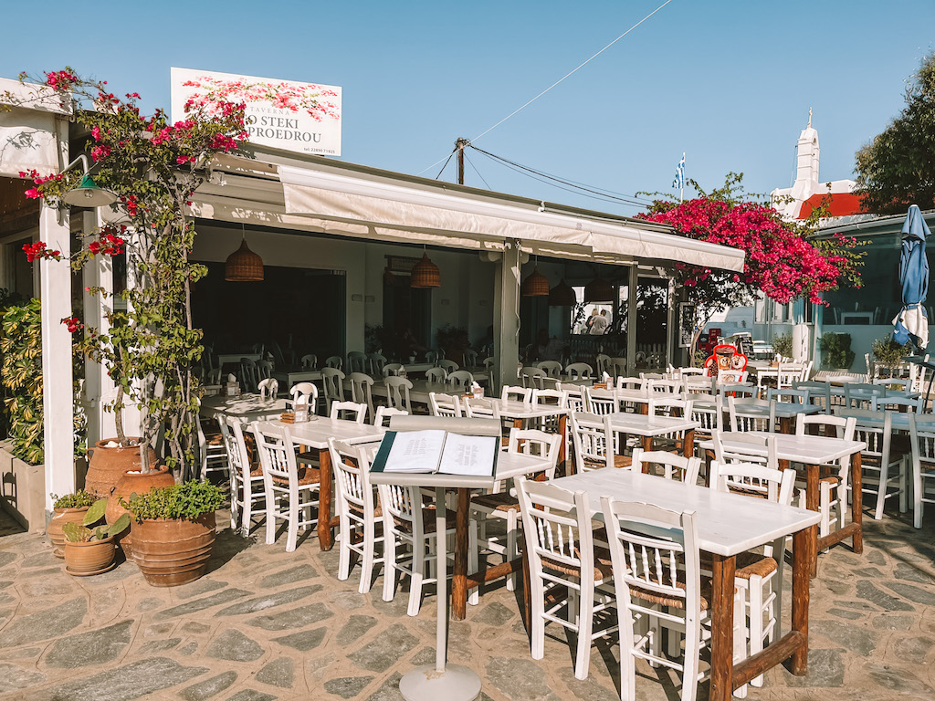 Idyllische Taverne mit weißen Stühlen und schönen Blumen in Ano Mera, Mykonos